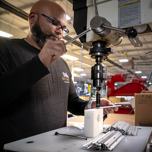 CDI Employee using drill press on part